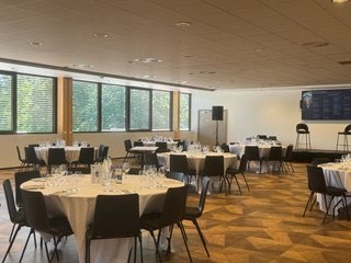 La Grande salle du Parc dressée de tables rondes nappées de blanc pour une réception